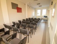 Sala szkoleniowa w Bydgoszczy z rzutnikiem oraz tapicerowanymi krzesłami z pulpitami