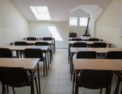 Sala szkoleniowa ze stołami w układzie szkolnym oraz tablicą suchościeralną 