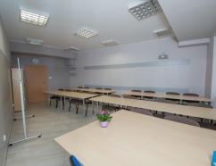Sala z przeznaczeniem do przeprowadzania konferencji, widok na krzesła tapicerowane w układzie szkolnym, rzutnik oraz tablice suchościeralną