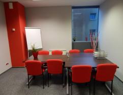 Mała sala szkoleniowa wyposażona w krzesła tapicerowane ze stołem w układzie konferencyjnym oraz tablice suchościeralną