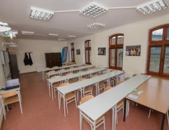 Sala szkoleniowa w Rybniku przy ulicy Korfantego, widok na krzesła ze stołami w układzie szkolnym oraz tablice multimedialną