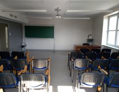 Sala szkoleniowa w Gdańsku przy al. Grunwaldzkiej, widok na krzesła tapicerowane z pulpitami, biurko prowadzącego oraz rzutnik multimedialny