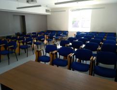 Sala szkoleniowa znajdująca się w budynku WSB w Gdańsku przy al. Grunwaldzkiej, widok na krzesła tapicerowane z pulpitami oraz rzutnik multimedialny
