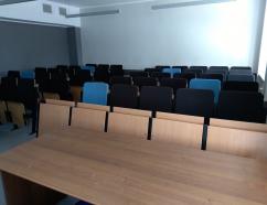 Sala szkoleniowa znajdująca się w budynku WSB w Gdańsku przy al. Grunwaldzkiej, widok na krzesła tapicerowane z pulpitami, biurko prowadzącego oraz rzutnik multimedialny