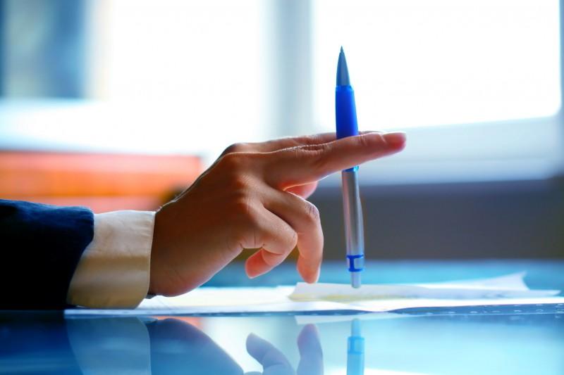 dłoń z długopisem na biurku